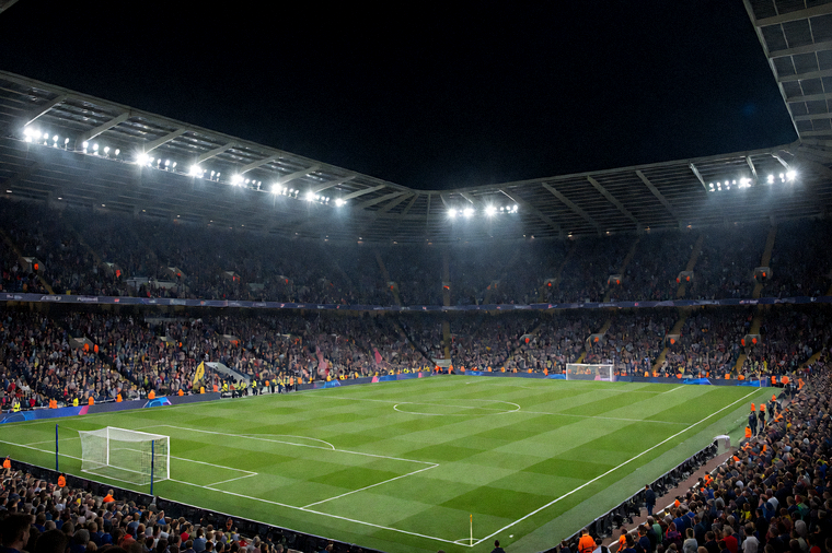 夜晚灯光下的足球场全景，看台坐满观众，比赛即将开始
